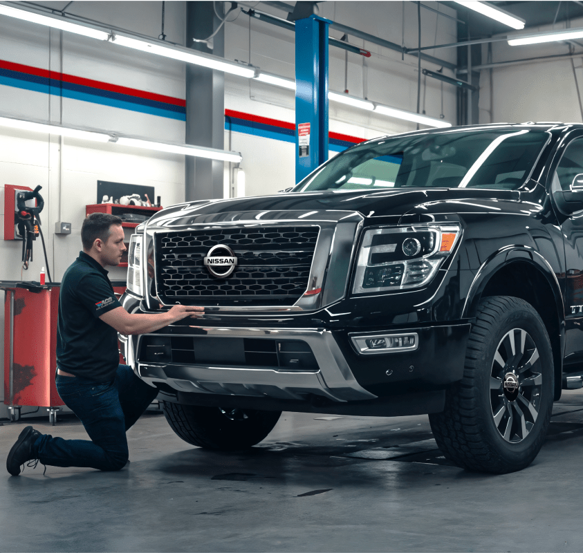 Mechanic inspecting black Nissan truck